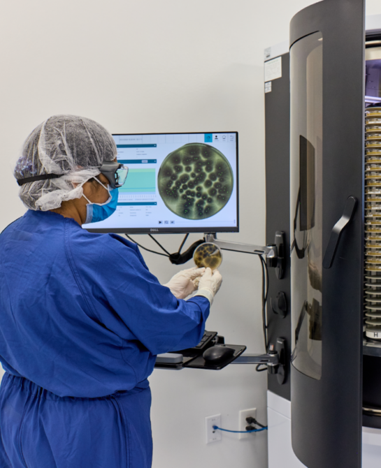 A worker looking at a machine that shows a microscopic view